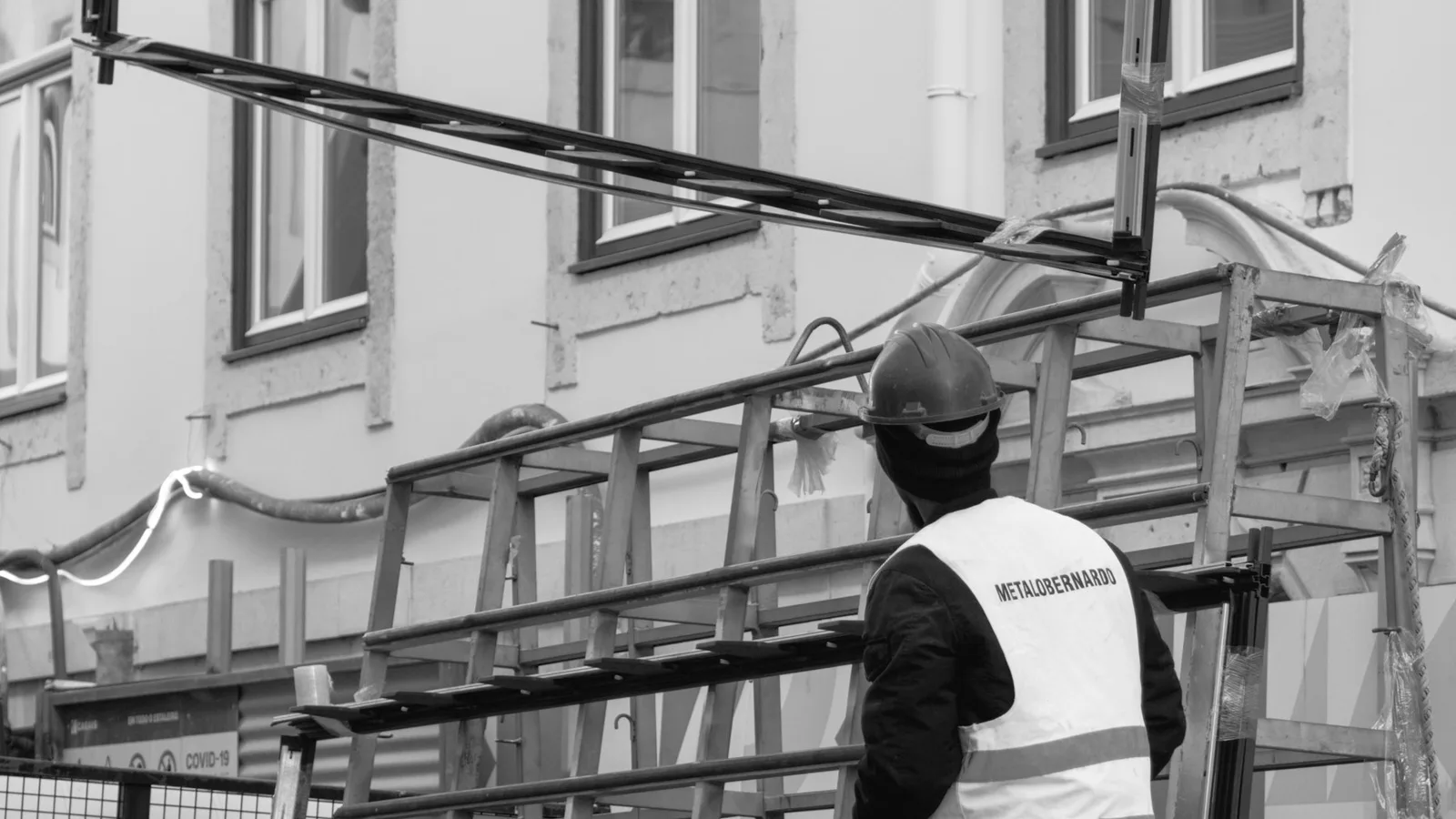 A construction worker handling a large window frame at a building work site