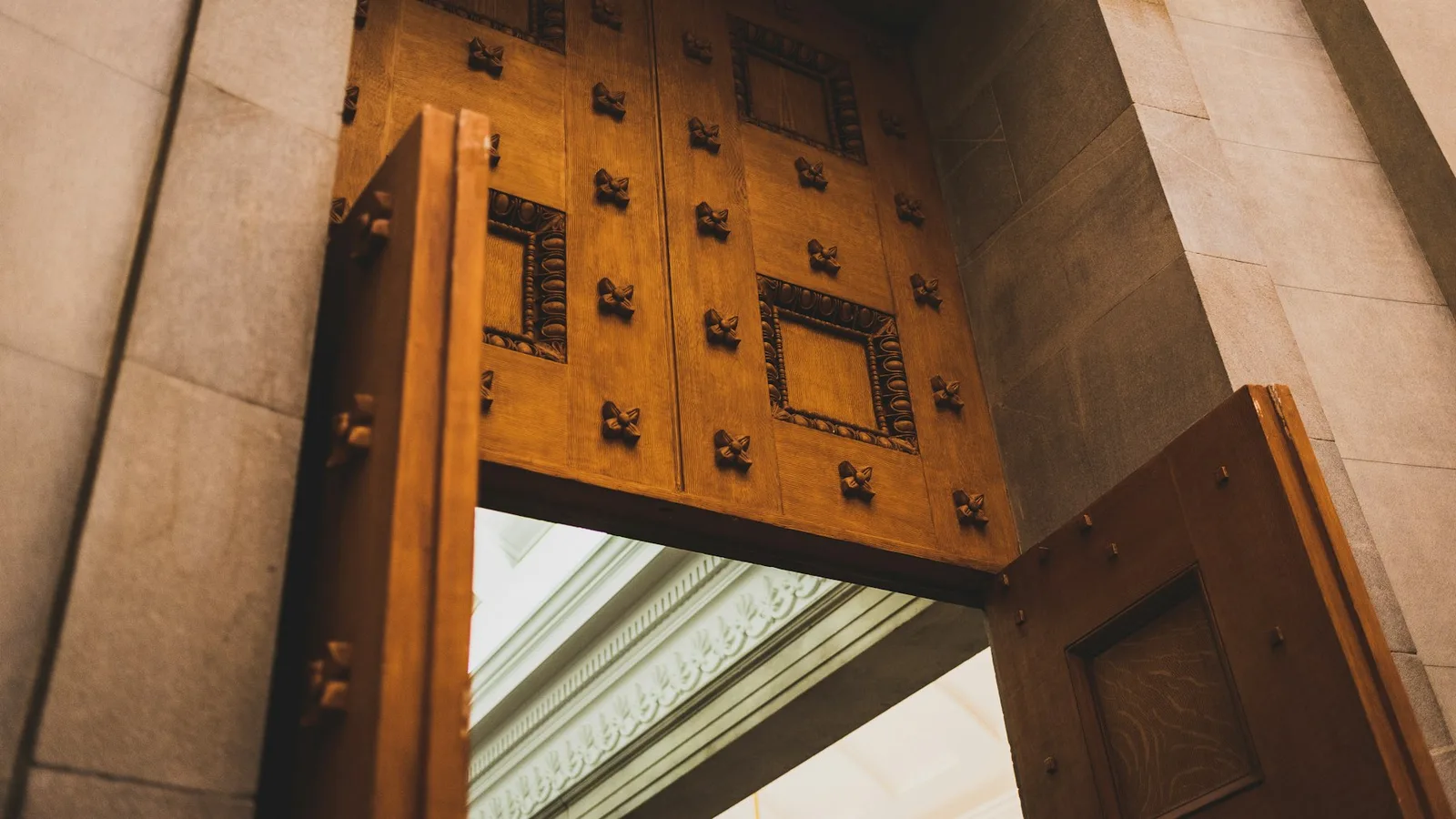 Open wooden door leaves projecting into a stone entrance